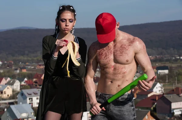 Chica comer plátano y hombre en gorra celebración de murciélago —  Fotos de Stock