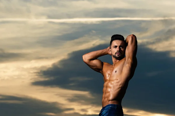 Atleta homem com corpo muscular no céu azul — Fotografia de Stock