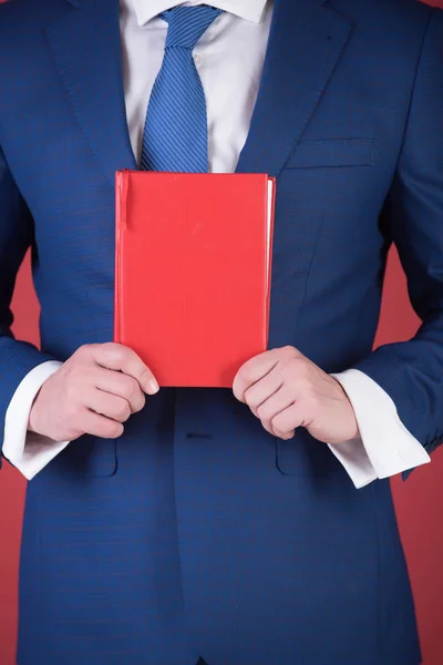 Libro rojo de lectura en la mano del joven o hombre de negocios — Foto de Stock