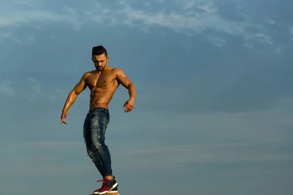 Cara com corpo muscular em óculos de sol no céu azul — Fotografia de Stock