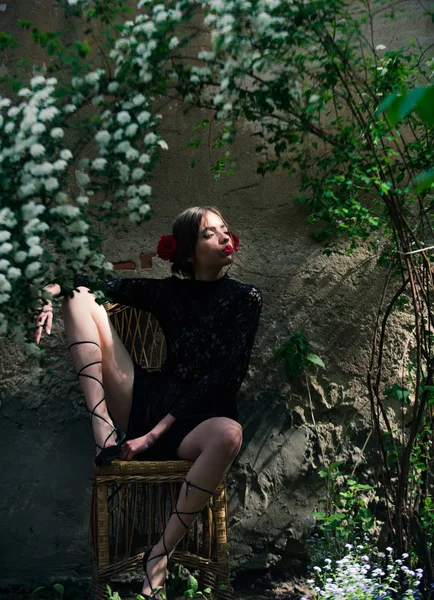 Дівчина в чорному, мереживна сукня сидить на плетеному кріслі — стокове фото