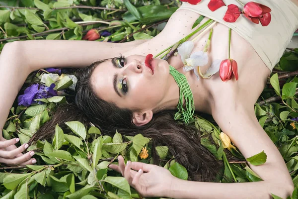 Mujer con maquillaje de moda con flores en hojas verdes — Foto de Stock