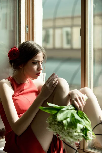 Bela menina espanhola sentada na janela com buquê de flores — Fotografia de Stock