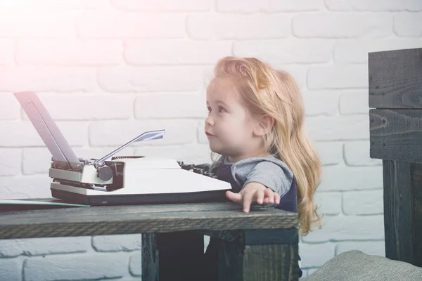 Journalist kid sitting at table and typing typewriter with paper — Stock Photo, Image