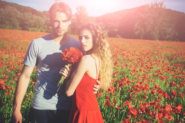 Uomo e ragazza con mazzo di fiori nel campo di papavero rosso — Foto Stock