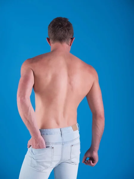 Uomo con schiena nuda in jeans alla moda su sfondo blu — Foto Stock