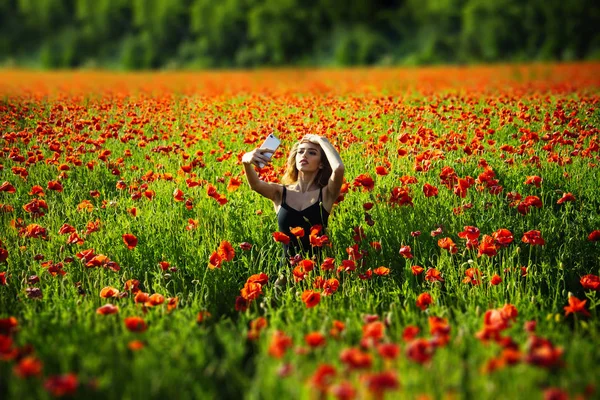 Champ de fleurs de pavot rouge et fille faisant selfie téléphone — Photo