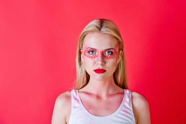 Mooie blonde vrouw met creatieve modieus make-up op rode achtergrond — Stockfoto