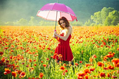 Kırmızı haşhaş alanın üzerinde pembe şemsiye ile mutlu kız