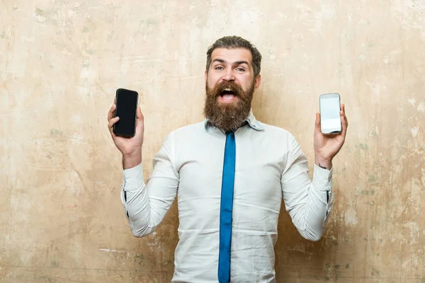 Mies tai hipster vertailla matkapuhelin ja älypuhelin — kuvapankkivalokuva