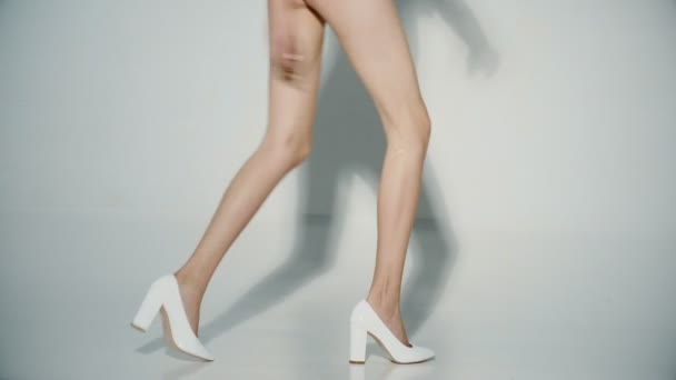 Sexy nohy v bílých botách chodit do studia. Metrová samice holé nahý nohy mladá dívka modelu tančit ve vysokých podpatků. Obchod s obuví. K nepoznání dívka s krásné nohy bez celulitidy