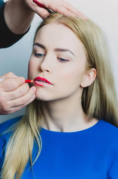 Artista masculino aplicando lápiz rojo en los labios de la mujer — Foto de Stock