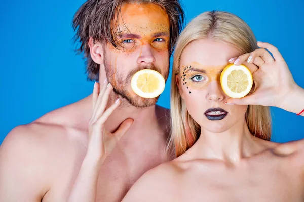 woman and man with makeup hold lemon