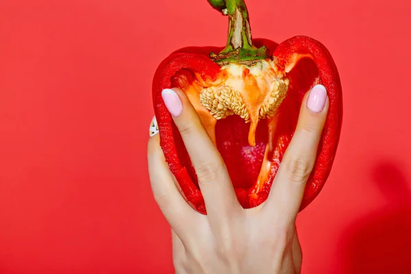 Paprika in hand van meisje op rode achtergrond — Stockfoto