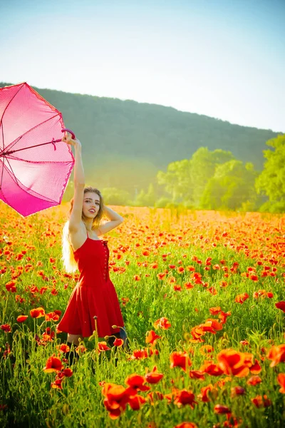 Kırmızı haşhaş alanın üzerinde pembe şemsiye ile mutlu kız