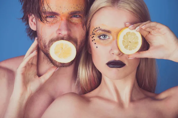 young couple of woman and man with makeup hold lemon