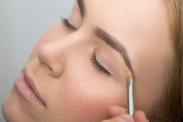 Girl with closed eyes getting makeup on eyelids — Stock Photo, Image