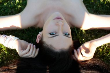 Güzel bir kız ya da güzel kadın yeşil çim üzerinde yalan