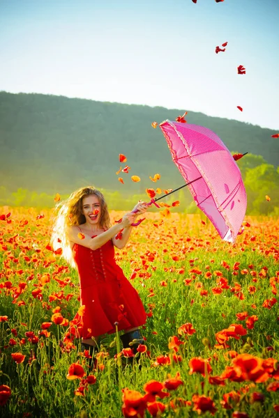 Glad tjej med rosa paraply över röda vallmofält — Stockfoto