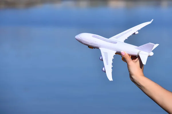 Plane white toy model in female hand on blue background