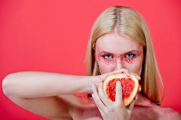 Grapefruit in handen van vrouw met creatieve modieuze make-up, vitamine — Stockfoto