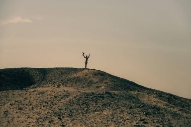 Kamera ve kazanan bir jest üstünde çöl tepe tepe olan adam