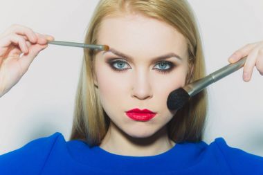 Kadının yüzündeki tozu ve makyaj uygulayarak fırçaları ile