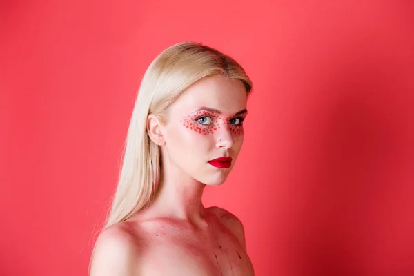 Vrouw met creatieve modieus make-up op rode achtergrond — Stockfoto