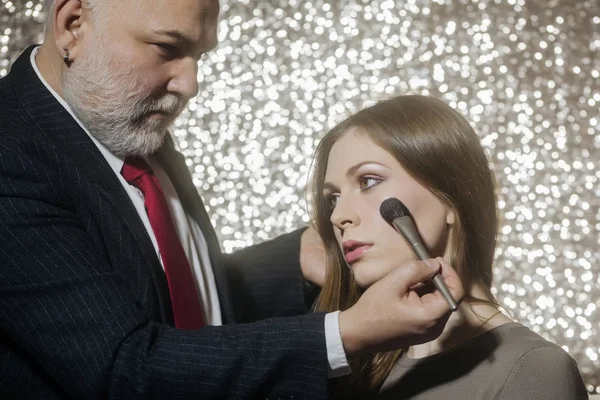 Artista de maquillaje profesional que trabaja con hermosa mujer joven, cuidado de la piel — Foto de Stock