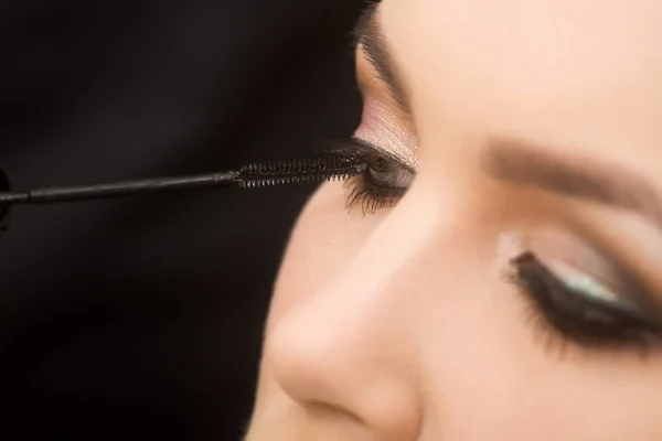 Ojos de chica conseguir rímel negro en las pestañas con cepillo — Foto de Stock