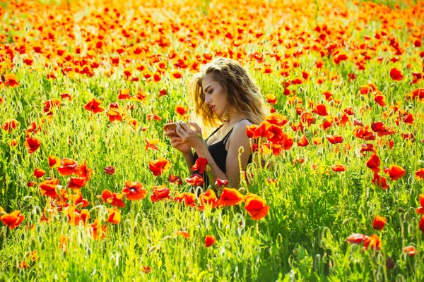 Flicka i fältet av vallmo gör selfie foto med telefon — Stockfoto