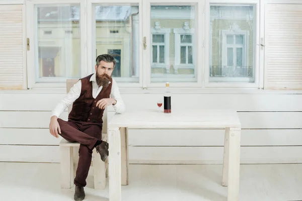 Şişe ve cam masa sandalye üzerinde oturan hipster — Stok fotoğraf
