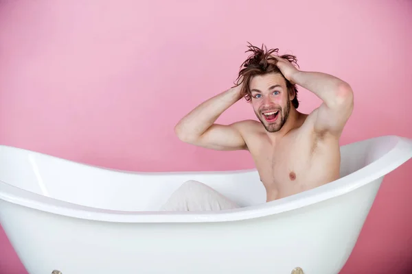 Joven guapo con cuerpo musculoso sentado en bañera blanca —  Fotos de Stock