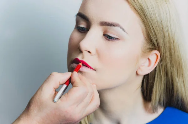 Mão masculina aplicando lápis vermelho nos lábios da mulher — Fotografia de Stock