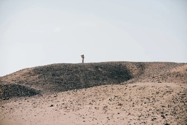 Man with camera on desert hill