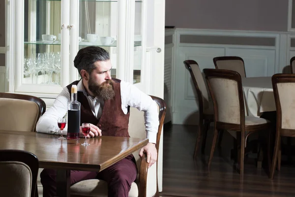 Homem sentado com garrafa e dois copos na mesa — Fotografia de Stock