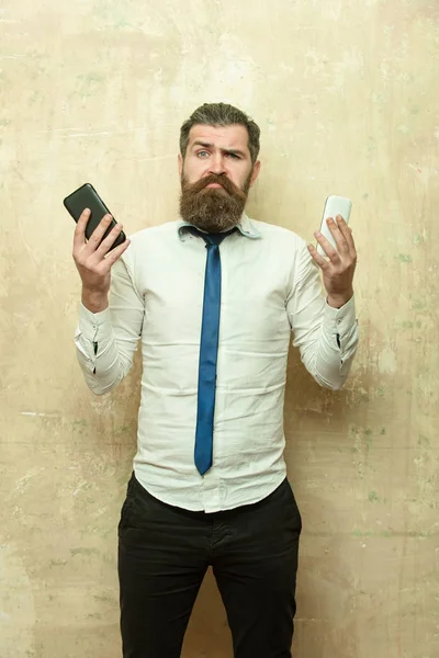 Johtaja tai parrakas mies verrata matkapuhelin ja älypuhelin — kuvapankkivalokuva