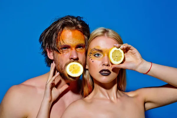 man and girl with makeup hold lemon