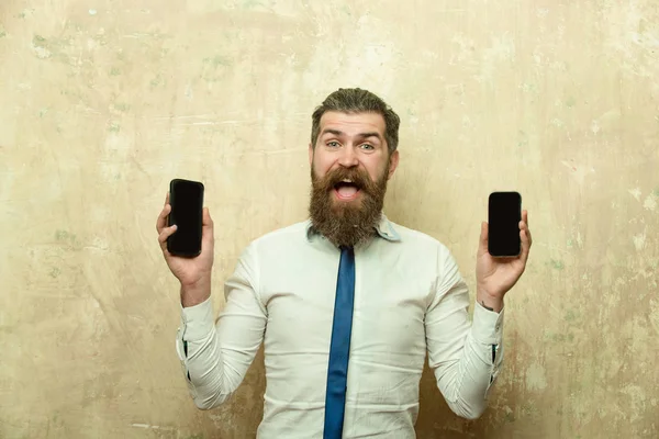 Homem barbudo ou hipster comparar telefone celular e smartphone — Fotografia de Stock