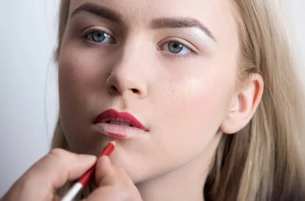 Menina recebendo lápis vermelho nos lábios pela mão masculina — Fotografia de Stock