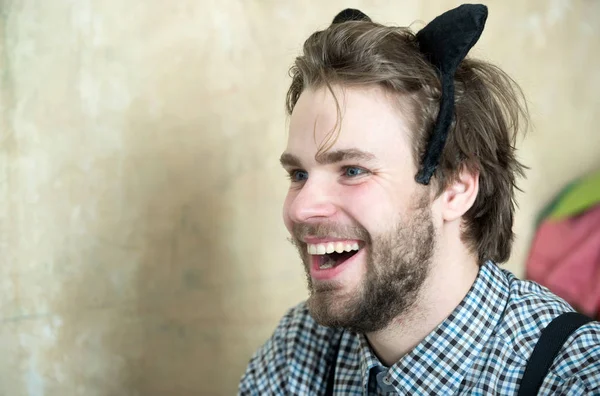 Man smiling with black cat ears headband on head