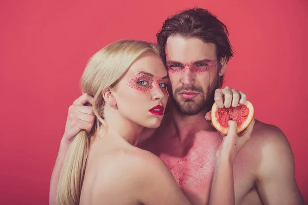 Молодая пара женщина и мужчина с макияжем держать грейпфрут — стоковое фото