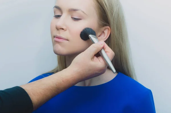 Chica conseguir polvo en la cara con el cepillo de maquillaje en la mano — Foto de Stock