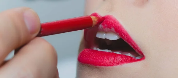 Lips getting red pencil makeup by male hand — Stock Photo, Image