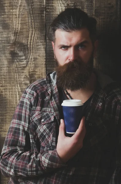Fruncir el ceño barbudo hipster posando con taza de plástico azul — Foto de Stock