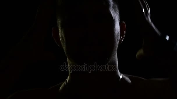 Man in het donker zingt emotioneel. Silhouetten van mannen, portret in donkere studio, schaduwen en verlichting, hoofd en handen. De zanger zingt nummer met emotie. Videoclip van onherkenbaar jonge kerel — Stockvideo