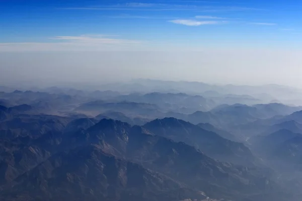 Vue aérienne de la montagne et du ciel bleu depuis la fenêtre de l'avion — Photo