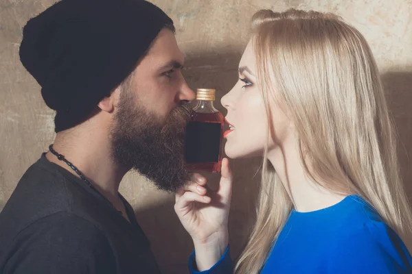 Hipster och flicka poserar med flaska likör — Stockfoto