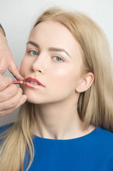 Visagiste masculino aplicando lápiz rojo en los labios de la chica —  Fotos de Stock