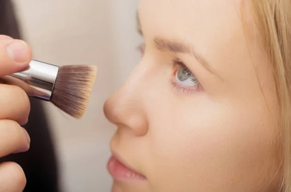 Meisje krijgen poeder op de huid van het gezicht met make-up borstel — Stockfoto